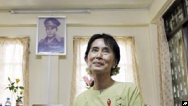 Pro-democracy leader Aung San Suu Kyi pauses during an interview with the Associated Press as a portrait of her father, independence hero Gen. Aung San, hangs on the wall at the National League for Democracy headquarters in Rangoon, Burma, 18, Nov. 2010.