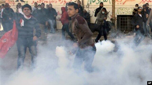 An Egyptian protester throws a tear gas canister fired by security forces during clashes near the Interior Ministry in Cairo, Egypt, Sunday, Feb. 5, 2012.