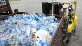 A man uses a forklift to move containers of plastic bottles at the recycling center 