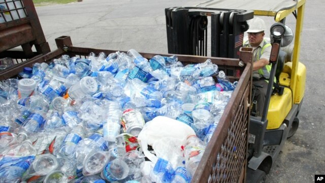 A man uses a forklift to move containers of plastic bottles at the recycling center 