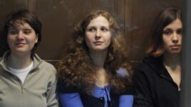 Members of the female punk band "Pussy Riot" (L-R) Yekaterina Samutsevich, Maria Alyokhina and Nadezhda Tolokonnikova sit in a glass-walled cage before a court hearing in Moscow October 10, 2012. 