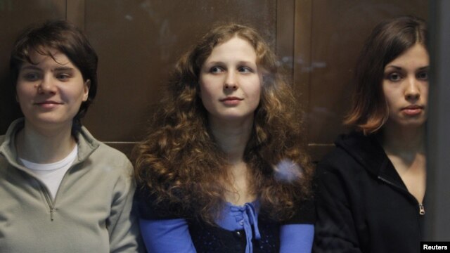Members of the female punk band "Pussy Riot" (L-R) Yekaterina Samutsevich, Maria Alyokhina and Nadezhda Tolokonnikova sit in a glass-walled cage before a court hearing in Moscow October 10, 2012. 
