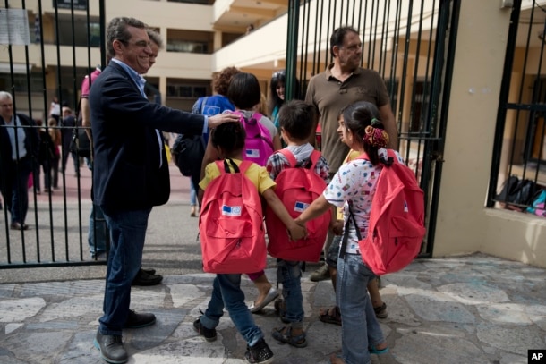 FILE - Refugee children enter a primary school in Athens on the first day of lessons under the new refugee schooling program, Oct. 10, 2016.
