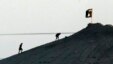 FILE - Militants with the Islamic State group are seen after placing their group's flag on a hilltop at the eastern side of the town of Kobani, Syria. 