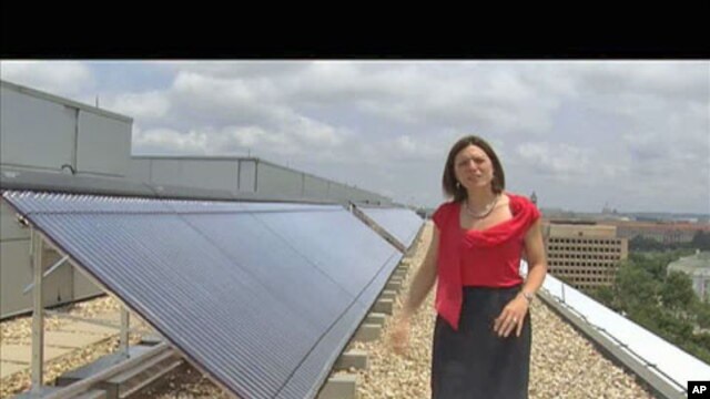 Meghan Chapple-Brown, director of Sustainability, stands by some of the solar hot-water systems that are on the rooftops of several buildings at George Washington University in urban Washington, D.C., June 2011