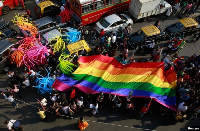FILE - Participants holding a rainbow flag pass through a junction during a gay pride parade, which is promoting gay, lesbian, bisexual and transgender rights, in Mumbai, Jan. 31, 2015.