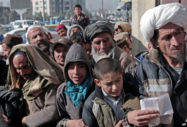 FILE - Afghan men and boys wait in line to receive their donated sacks of wheat distributed by the World Food Program in Kabul, Afghanistan, Dec. 15, 2013.