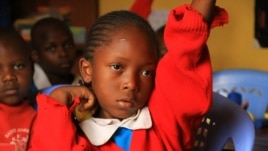 A student raises her hand to ask a question during class at the Kibera School for Girls in Nairobi, Kenya, March 19, 2013.(J. Craig/VOA)