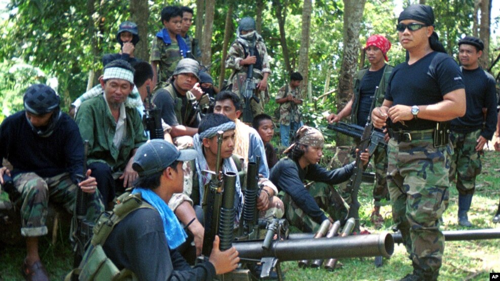 FILE - In this undated file photo, Abu Sayyaf spokesman Abu Sabaya, right foreground, stands with militants in Basilan, the Philippines.