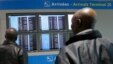 Men look at an information screen displays that Air France flight AF755 from Conakry has arrived at Charles de Gaulle International Airport in Roissy, near Paris, Oct. 18, 2014. 
