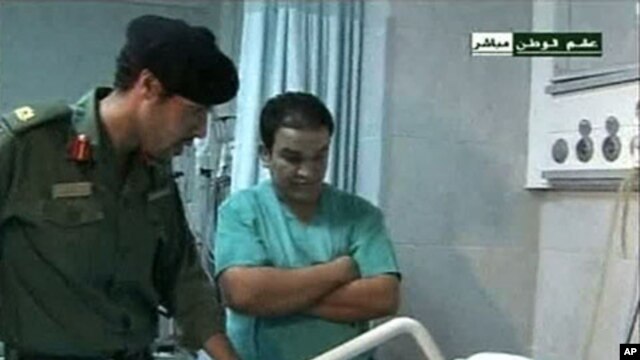 Still image from video footage by Libyan state television on August 9, 2011, shows what it says is Khamis Gadhafi (L) visiting wounded Libyans in a hospital
