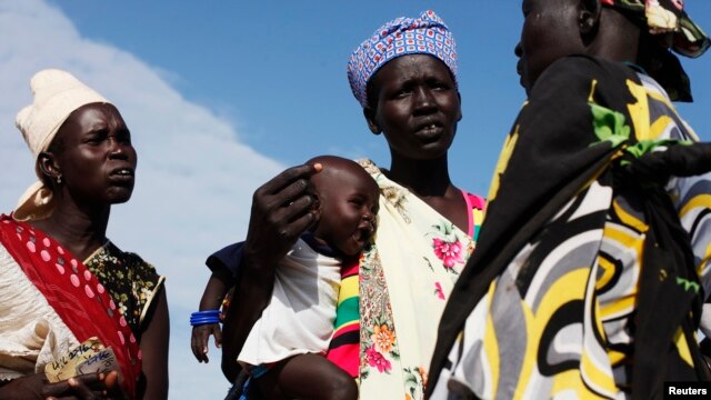 FILE - A woman carries a baby as she talks with other women talk at a food distribution center in Minkaman, Lakes State, South Sudan, June 27, 2014. Activists are calling on the leaders of the Transitional Government of National Unity to include more women in government roles.