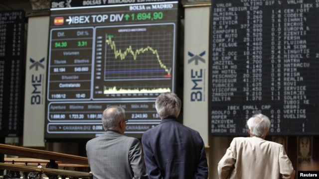 Traders look at electronic boards at the stock exchange in Madrid, June 11, 2012. 