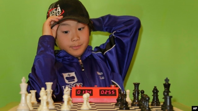 Maximillian Lu adjusts his cap as he toys with a chess set during an interview, Nov. 16, 2015, in Armonk, N.Y. The 10-year-old recently became the youngest chess master ever in the United States.