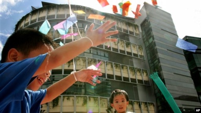 Anak-anak bermain di depan gedung Universitas Manajemen Singapura. (AP/Wong Maye-e)