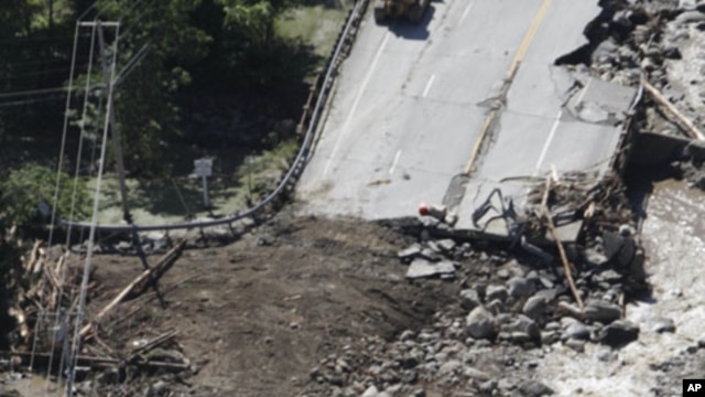 People gather alongside workers making repairs on Route 4 in Killington, Vermont, Aug. 30, 2011