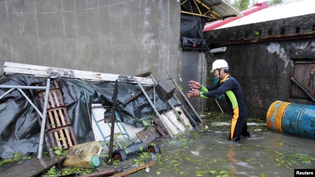 A man clears debris near his house flooded by Typhoon Saola in Wujie in Ilan County, Tawian, August 2, 2012.