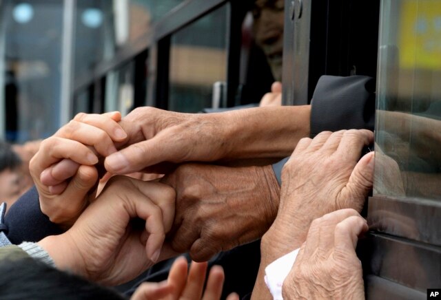 South Koreans and their North Korean relatives on a bus grip their hands each other to bid farewell after the Separated Family Reunion Meeting at Diamond Mountain resort in North Korea, Oct. 22, 2015.