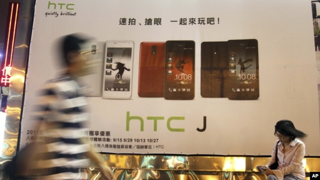 Man walks past an advertising board of Taiwan's smartphone maker HTC Corp. in Taipei, Taiwan, October 25, 2012.