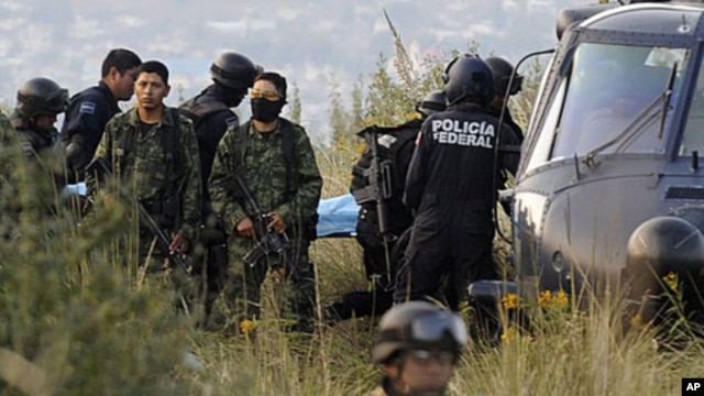 Soldiers stand guard as federal police officers carry a stretcher with the body of a victim of a helicopter crash in which Mexico's Interior Minister Francisco Blake Mora and seven others were killed near Mexico City, November 11, 2011.