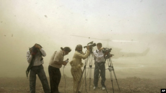 Journalists take cover as the helicopter carrying the late U.S. special envoy Richard Holbrooke lands in Mardan district, about 120 km  northwest of Pakistan's capital Islamabad. (FILE)