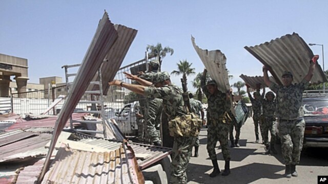 Egyptian Army soldiers clear away scrap metal used by protesters during clashes outside the Ministry of Defense in Cairo, Egypt, May 5, 2012.