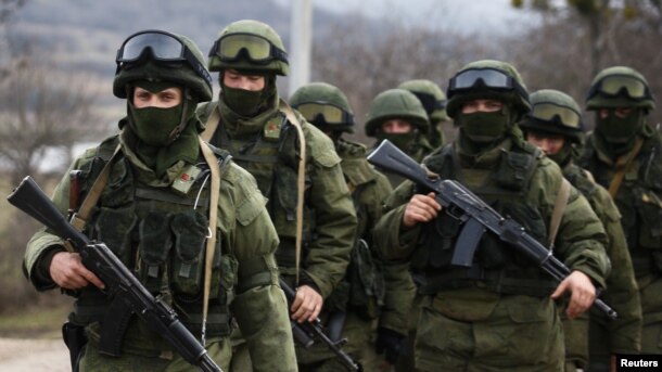 FILE - Armed men, Russian servicemen as the Kremlin later admitted, stand guard outside a Ukrainian military base in Perevalne, Crimea, March 9, 2014. Moscow's initial denials that the men were its soldiers was seen as part of its disinformation strategy.