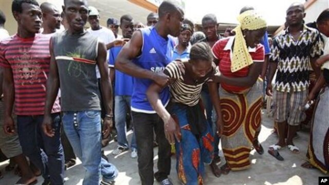 Neighbors help lead away a woman after she collapsed in grief as she visited the local opposition party office where her brother was killed in an overnight attack, in the Yopougon neighborhood of Abidjan, Ivory Coast, 02 Dec 2010