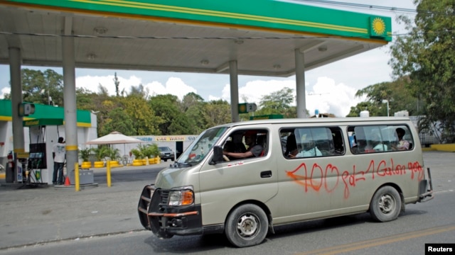 A minivan used for public transportation drives past a gasoline station in Port-au-Prince, Feb. 8, 2015.