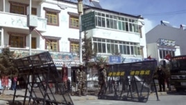 In this photo taken on Monday, Feb. 27, 2012, Chinese paramilitary police and riot police stand guard near barricades set up along the main street of Ngaba.