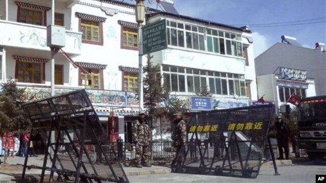 In this photo taken on Monday, Feb. 27, 2012, Chinese paramilitary police and riot police stand guard near barricades set up along the main street of Ngaba.