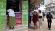 Pedestrians walk past an M-Pesa shop in downtown Nairobi, Kenya, May 12, 2009. 