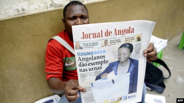 An Angolan newspaper street seller holds up a copy of the national paper in the street of Luanda, September 1, 2012. 
