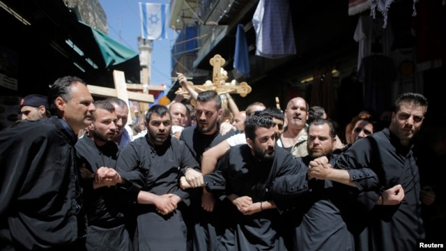 Fieles cristianos se toman de los brazos durante la procesión del Viernes Santo en la Via Dolorosa en Jerusalén.