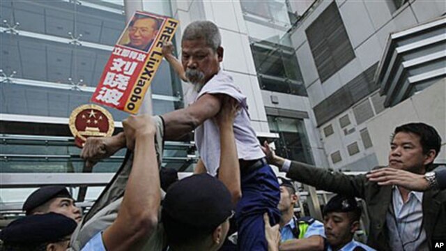 A pro-democracy protester holding the picture of the jailed Chinese dissident Liu Xiaobo, tries to climb across the police line during a demonstration at the China Liaison Office in Hong Kong, Nov 11, 2010 (file photo)