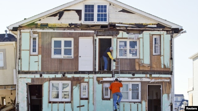 Warga menaiki tangga di luar rumahnya yang hancur karena Badai Sandy di Ortley Beach, New Jersey (7/1). (Reuters/Tom Mihalek)