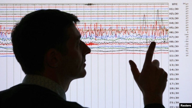 Un sismólogo apunta un gráfico que registra la magnitud de un temblor.