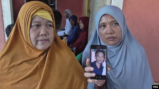 Roslian, 44 (kanan), memperlihatkan foto putranya, Rinaldi, salah satu dari 10 WNI yang disandera oleh kelompok gerilyawan Abu Sayyaf di Filipina selatan. (VOA/Yoanes Litha).