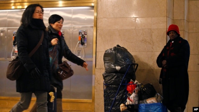 Commuters pass by a homeless person in Grand Central Terminal in New York, January 25, 2013. Sequestration could force deep cuts to social programs, including homeless services.