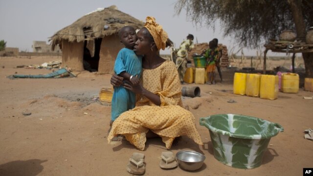In this Tuesday, May 1, 2012 photo, Maryam Sy comforts her 2-year-old son Aliou Seyni Diallo, the youngest of nine, after a neighbor gave him dry couscous to stop him from crying with hunger, in the village of Goudoude Diobe, in the Matam region of northe