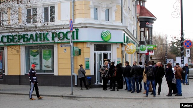 Người dân đứng xếp hàng để vào một chi nhánh của ngân hàng Sberbank, Nga, tại thành phố Simferopol của Crimea. 
