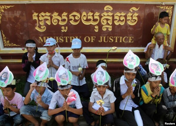 FILE - Children of Boeung Kak women protesters wear portraits of their mothers around their foreheads as they pray at a protest in front of the Ministry of Justice in Phnom Penh.