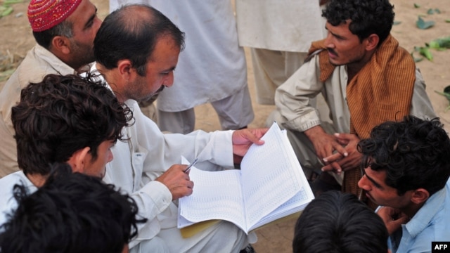 Naim ullah Khattak (L), an Election Commission of Pakistan (ECP) worker, verifies voters using a list from the Computerized National Identity Card (CNIC) database in the outskirts of Islamabad on Sept. 12, 2011.