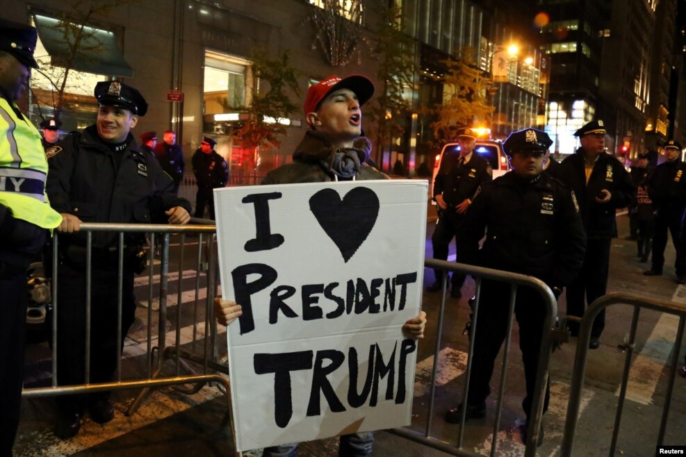 一位拥护川普者同抗议川普者对喊，他拿着标语&ldquo;我爱川普总统&rdquo;（2016年11月11日）