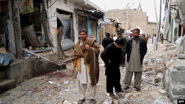 Onlookers stand over the site of a bomb blast outside a Shiite Muslim mosque in Hangu, February 1, 2013.