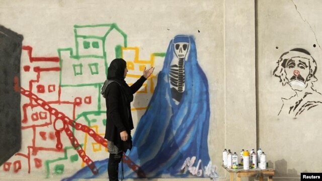 Afghan artist Malina Suliman paints graffiti on a wall in Kandahar city December 30, 2012.
