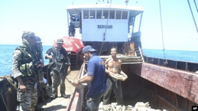 Handout photo shows members of Philippine Army inspecting one of eight Chinese fishing boats spotted in the Scarborough Shoal, a small group of rocky formations whose sovereignty is contested by the Philippines and China, in the South China Sea, about 124
