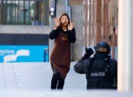 Một con tin chạy về phía cảnh sát đang bao vây bên ngoài quán café Lindt ở khu vực Martin Place, Sydney, Australia, 15/12/2014.
