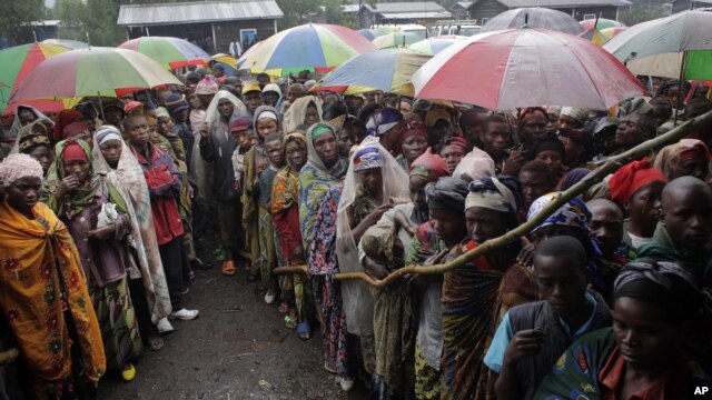 Internally displaced Congolese men and women wait for a World Food Program energy biscuits to be distributed in Kibati, north of Goma, eastern DRC, August 8, 2012.