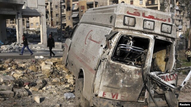 Residents walk past a damaged emergency vehicle in Aleppo, Syria, January 1, 2013.